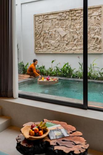 a man sitting in a pool with a bowl of fruit at Greha Natha Villa Ubud in Ubud