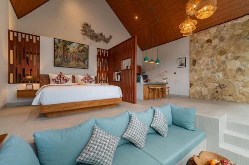 a bedroom with a bed and a blue couch at Greha Natha Villa Ubud in Ubud