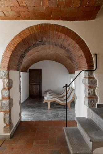 a brick archway with a bench in a room at Relais Vignale & Spa in Radda in Chianti