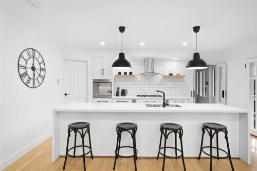a white kitchen with black bar stools at a counter at Best of Yarra Valley and Kinglake National Park 