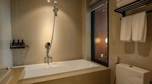 a bathroom with a bath tub next to a toilet at The Scenic Hotel in Phnom Penh