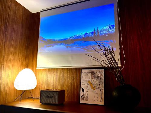 東京にある中野駅南inn Nakano Station South Innのランプと絵が飾られた壁の大きなスクリーン