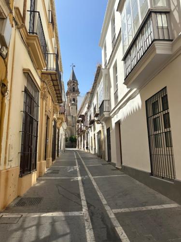an empty alley with a church in the distance at Apartamento Vinoble Jerez in Jerez de la Frontera