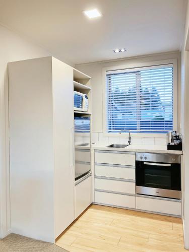 a white kitchen with a sink and a window at Anchorage Motel Apartments in Te Anau