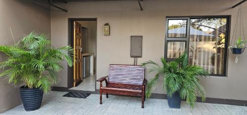 a wooden chair sitting outside of a house with two plants at Miláns Bed and Breakfast in Katima Mulilo