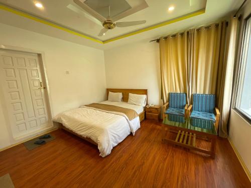 a bedroom with a bed and two blue chairs at Sarfaranga Residency in Skardu