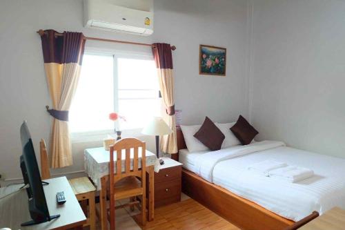 une chambre avec un lit, un bureau et une télévision dans l'établissement The Best House&Hostel, à Ban Don Muang (1)