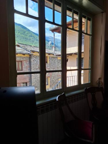 a window with two chairs looking out of it at Casa Editta in Bobbio Pellice