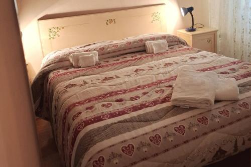 a bed with a red and white blanket and pillows at Casa Editta in Bobbio Pellice