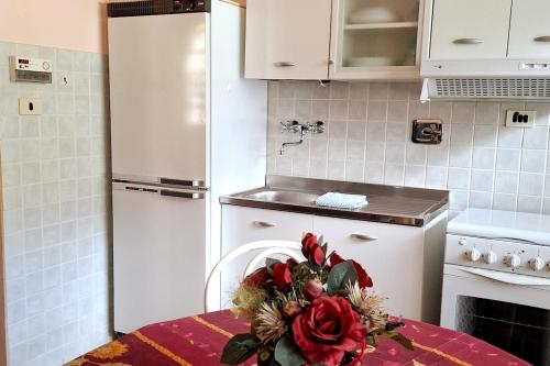 a kitchen with a white refrigerator and a table with flowers at Casa Editta in Bobbio Pellice