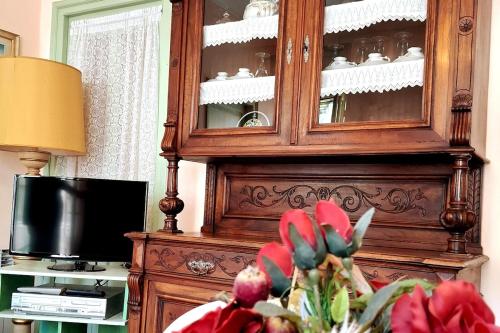 a large wooden cabinet in a living room with a flower at Casa Editta in Bobbio Pellice