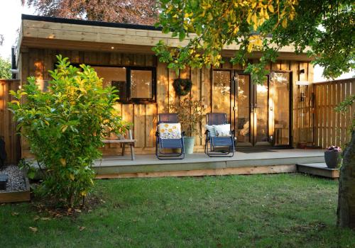 two chairs and a table on a porch of a house at Luxury Chestnut Lodge with Hot Tub and Games Room in Toppesfield