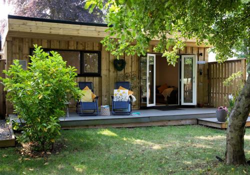 a house with a porch with blue chairs on it at Luxury Chestnut Lodge with Hot Tub and Games Room in Toppesfield