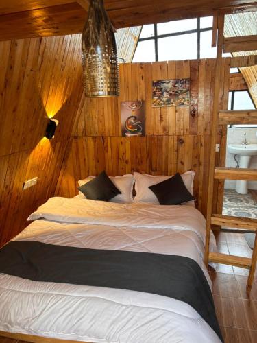 a bedroom with a large bed with wooden walls at Kaasham Cabin Nanyuki in Nanyuki