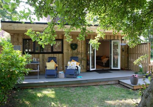 a wooden house with two chairs and a table at Luxury Chestnut Lodge with Hot Tub and Games Room in Toppesfield