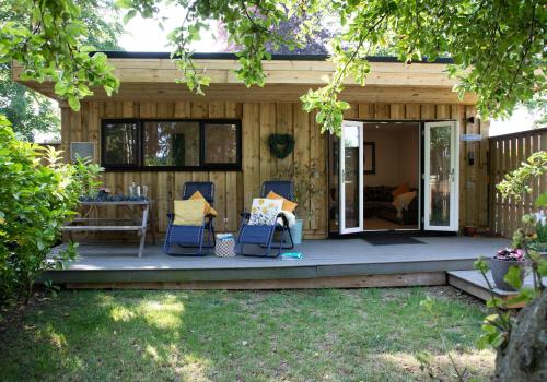 a house with a porch with chairs and a table at Luxury Chestnut Lodge with Hot Tub and Games Room in Toppesfield