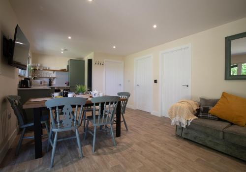 a kitchen and living room with a table and chairs at Luxury Chestnut Lodge with Hot Tub and Games Room in Toppesfield