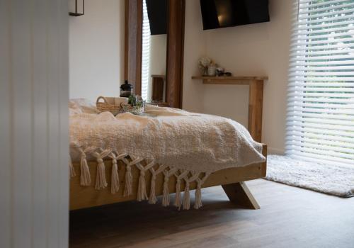 a bedroom with a bed with a comforter and a window at Luxury Chestnut Lodge with Hot Tub and Games Room in Toppesfield
