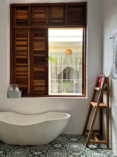 a bath tub in a bathroom with a window at à Bleu Hoian in Tân Thành (1)