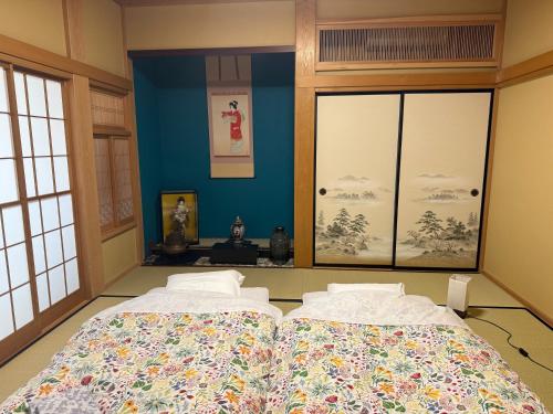 two beds in a room with blue walls and windows at Eishinan 栄進庵 in Fuji