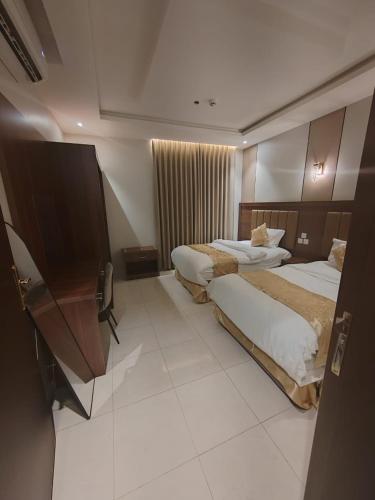a hotel room with two beds and a television at نيلوفر فور محايل عسير in Muhayil