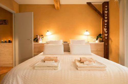 une chambre avec un lit blanc avec des serviettes dessus dans l'établissement Absolut Oiseaux, à Parisot