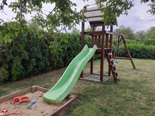 a playground with a green slide and a tower at Hétkanyar Vendégház in Nagyvázsony