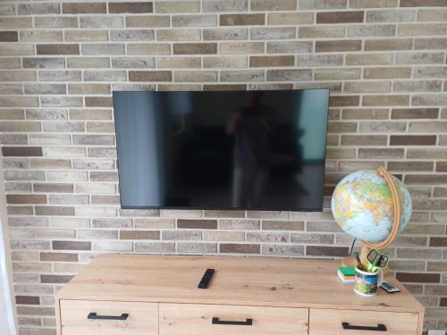 a television on a brick wall with a wooden table at Willa Przygoda in Żukowo