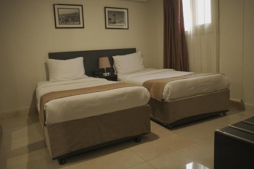 a hotel room with two beds and a window at NewCity Hotel & Suites in Cairo