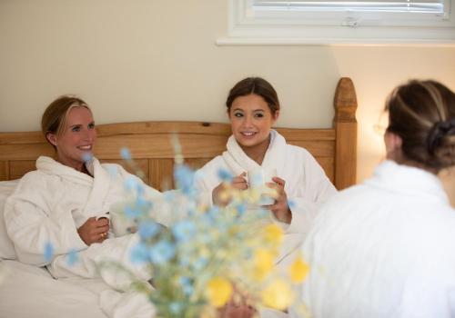 two women in robes sitting in a bed at Luxury Chestnut Lodge with Hot Tub and Games Room in Toppesfield