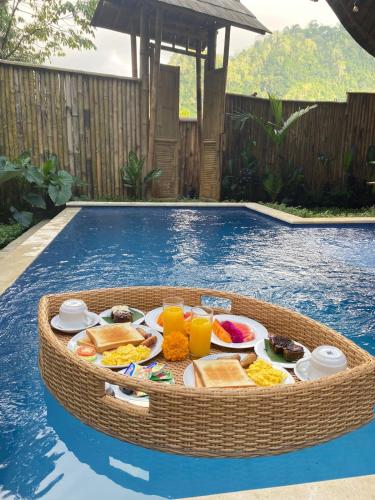 a tray of food on a table in a pool at Hidden Bamboo Village in Selat