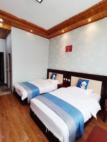 two beds in a room with white and blue at Emeishan Moon Bay Hotel in Emeishan