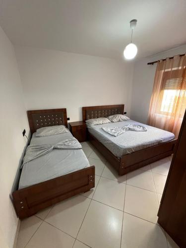 two beds sitting in a room with at Apartament Eljo in Çorovodë