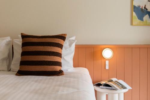 a bed with a pillow and a remote control on a table at The Lodge At The Denmark Hotel in Denmark