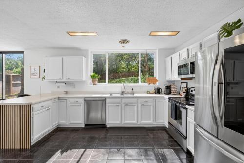a kitchen with white cabinets and a large window at The Palms Mirage House home in Millman