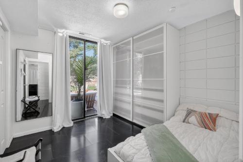 a white bedroom with a bed and a large window at The Palms Mirage House home in Millman