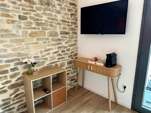 a room with two tables and a tv on a stone wall at Les Rubys, spas privatifs in Tarcenay