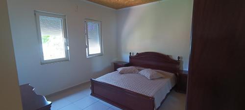 a small bedroom with a bed and two windows at Lake of Diber in Debar