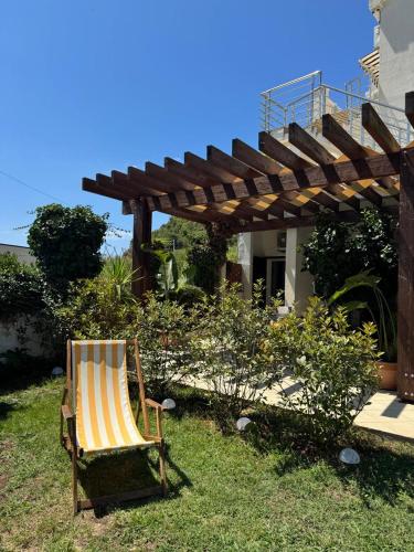a chair sitting in the grass under a wooden pergola at Apartments Villa Marija in Petrovac na Moru