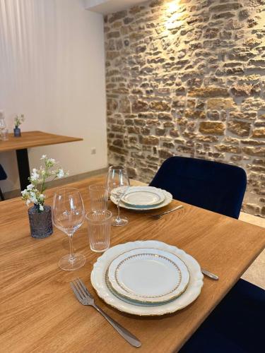 a wooden table with plates and wine glasses on it at Les Rubys, spas privatifs in Tarcenay