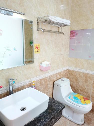 a bathroom with a white sink and a toilet at Emeishan Moon Bay Hotel in Emeishan