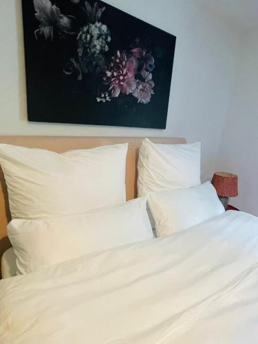 a bed with white pillows and a painting on the wall at Naturerlebnis direkt am Traumpfad in Andernach