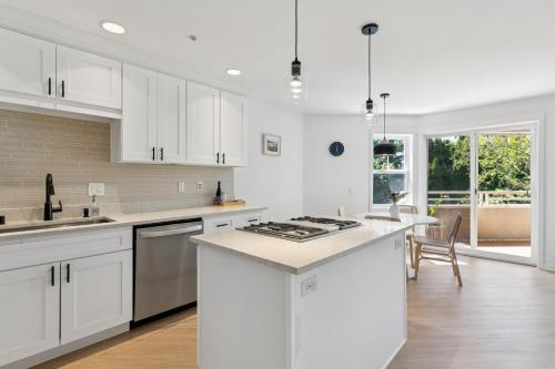 a white kitchen with white cabinets and a kitchen island at Walkable Seattle Gem Close To Everything condo in Seattle