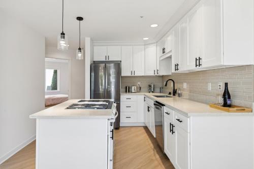 a white kitchen with white cabinets and a refrigerator at Walkable Seattle Gem Close To Everything condo in Seattle