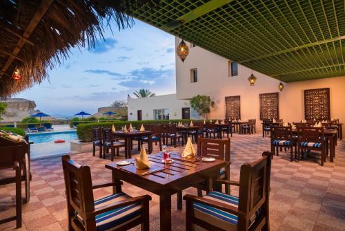 a restaurant with tables and chairs and a pool at Sur Plaza Hotel in Sur