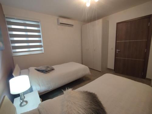 a small bedroom with two beds and a window at San Pawl Lodge Hostel in St Paul's Bay