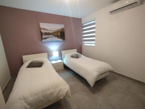 two twin beds in a room with a window at San Pawl Lodge Hostel in St Paul's Bay