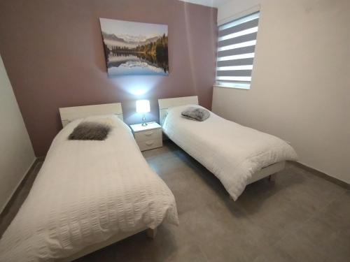 two twin beds in a room with a window at San Pawl Lodge Hostel in St Paul's Bay