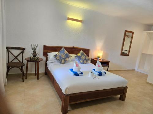 a bedroom with a bed with two desserts on it at Alona Garden Suites in Panglao