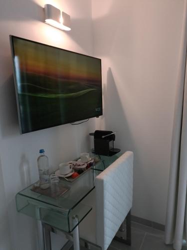 a flat screen tv hanging on a wall with a glass table at B&B Maison Durbois in Durbuy